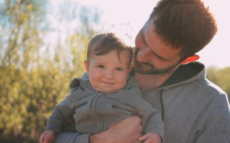 Cute baby boy on his dad's shoulders walking on road outdoors, sensitivity to the nature concept