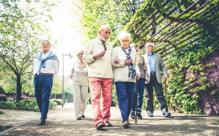 Group of senior people with some diseases walking outdoors - Mature group of friends spending time together